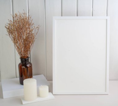 Beyaz poster çerçevesi, mumlar ve güzel Lagurus ovatus kurutulmuş çiçekleri modern cam vazo kompozisyonu ile beyaz ahşap masa odasının iç kısmı üzerine yerleştirin. 