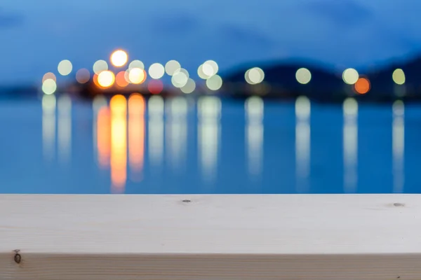 Färgglada oskärpa bokeh nattlamporna över havet med emty trä golv — Stockfoto