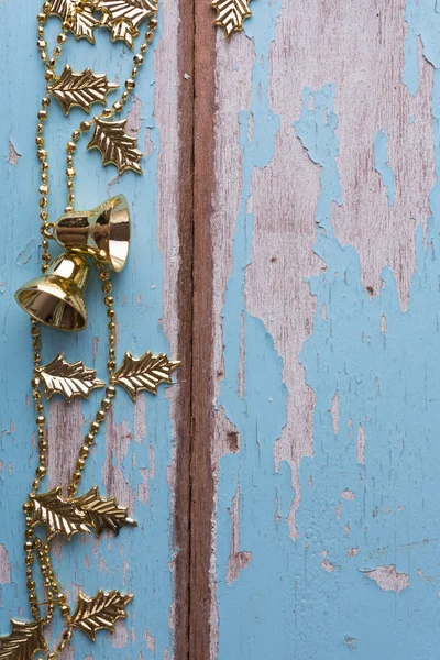 Cadena de campana de oro de Navidad decorativa en grunge respaldo de madera azul —  Fotos de Stock