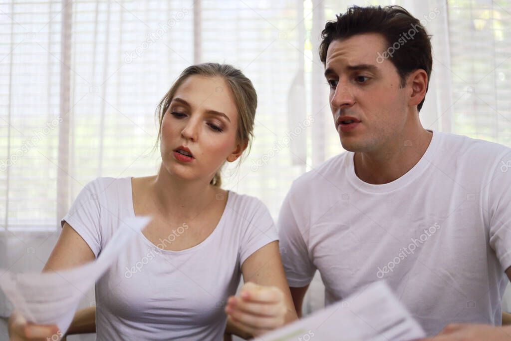 Unhappy young couple feeling worried about the cost for credit card bills at home.