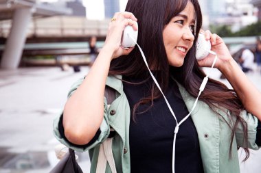 Güzel Asya Kadınlar mutlu ve gülümseme portre ve yürüyüş Caddesi üzerinde müzik dinleyin.