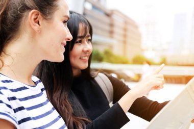 Genç kadınlar kağıt harita üzerinde turistlere ilgi gösteriyor.