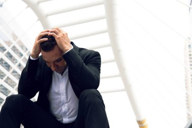 İş adamı üzgün oturuyor ve şehrin dışında düşünüyor..