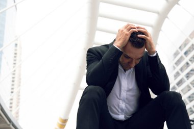 İş adamı üzgün oturuyor ve şehrin dışında düşünüyor..