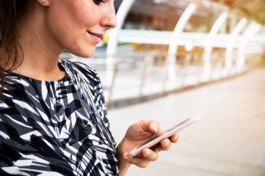 Güzel kadın gülümseme portre ve cep telefonu street yürüyüş üzerinde oynama.