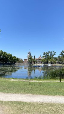 Önünde ördekler yüzen Tajamar rezervuarının huzurlu manzarası ve parlak mavi gökyüzünün altında ikonik El Tajamar saat kulesi.