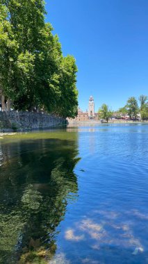 Önünde ördekler yüzen Tajamar rezervuarının huzurlu manzarası ve parlak mavi gökyüzünün altında ikonik El Tajamar saat kulesi.
