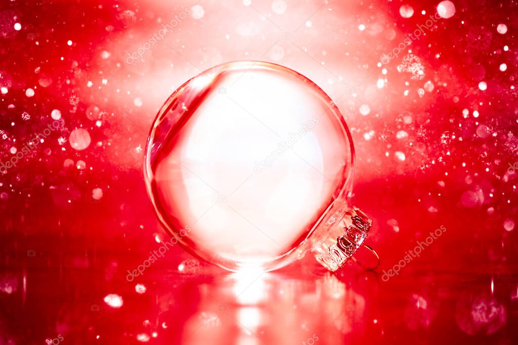 Clear glass Christmas ornament on red glittering lights background with blank empty space