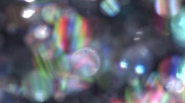 Işıl ışıl parlayan gökkuşağı yansıması ile parlak yüzen parçacıklar ile yumuşak ve bulanık bokeh parıltılı arkaplan yavaş hareket.