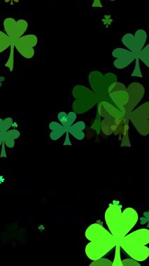 Aziz Patrick Günü arkaplanında siyah üzerine parıldayan çeşitli yeşilliklerle yoncalar vardı. Aziz Patrick gününü kutlamak için yeşil bir arkaplan arayan üç yapraklı yonca parçacıkları.