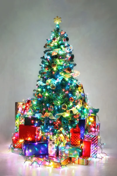 Geschmückter Weihnachtsbaum mit bunten Lichtern, umgeben von Pre — Stockfoto