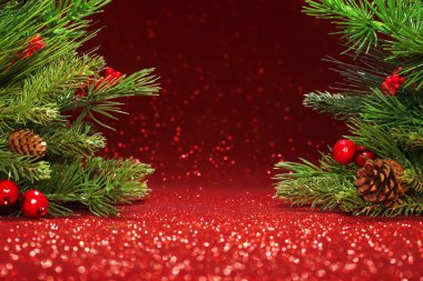 Parlak kırmızı arka planda Noel ağacı dalları