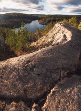 Kuzey manzarası, ladin yeşil ormanları arasında mavi göl. Karelian Isthmus 'un doğası ve Üçgen Gölü' nün kayaları tepeden görünüyor.