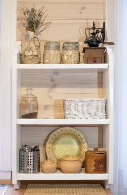 Mutfakta İskandinav kırsal beyaz ahşap raf. Cam kavanozlar, sürahiler ve çömleklerle