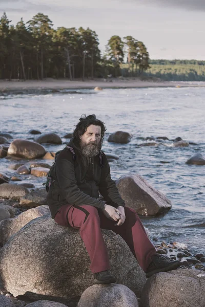 Een Volwassen Man Met Een Baard Zit Stenen Bij Zee — Stockfoto