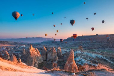 29 Mart, 21 Goreme Kapadokya Sıcak hava balonları yaz mevsiminde kumtaşı dağlarının üzerinden pembe gündoğumunda uçuyor.