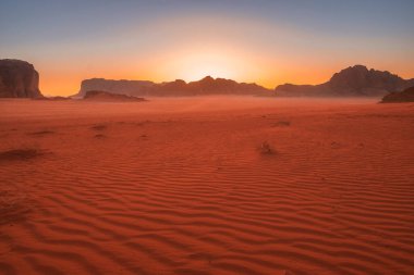 Ürdün 'deki Wadi Rum' un kırmızı çölünde güzel bir gün batımı. Kumda desenler var.