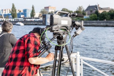 Tripodun üzerinde büyük bir profesyonel televizyon kamerası olan operatör.