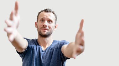 Dost canlısı mutlu adam, gri arka planda fotokopi çekilen bir kucaklaşma için ellerini kameraya çekiyor.