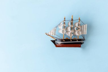 Açık mavi arka planda tahta yelkenli teknenin maketi, boşluğu kopyala