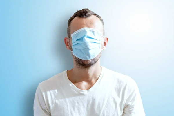 portrait of a man in a medical disposable mask all over his face on a blue background
