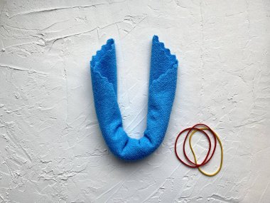Çocuklar için mavi mikrofiber kumaş ve kauçuk bant hayali bir çizgi film canavarı yapmak için adım adım talimatlar verir.