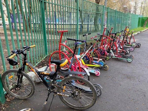Gyermekszállítás az iskola melletti parkolóban, kerékpárok és robogók. — Stock Fotó