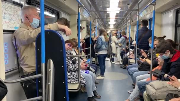 คนในรถไฟใต้ดินสวมหน้ากากและมองไปที่อุปกรณ์ของพวกเขา . — วีดีโอสต็อก