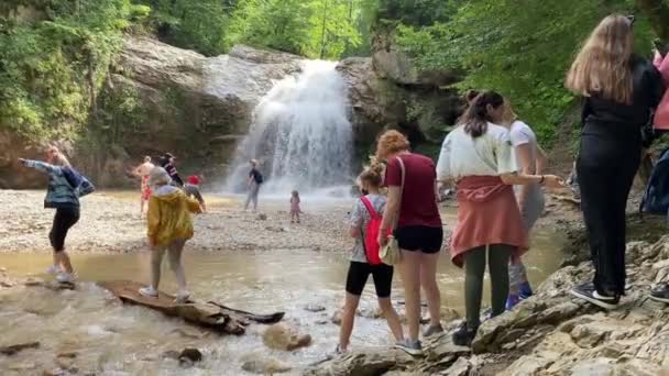 Adygea, Russland, Juli 2021, Menschen in Sommerkleidung gehen vorsichtig über den Fluss — Stockvideo