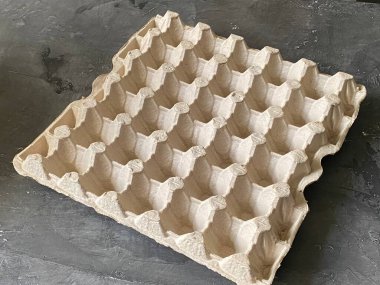 Boş bir kutu tavuk yumurtası, gri arka planda kare şeklinde..