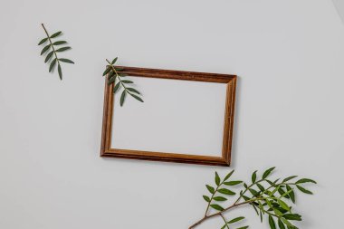 Boş kahverengi ahşap kenar, el işi kağıtları ve beyaz masa arkasında izole edilmiş yeşil dallar. Yaz düğün kırtasiyesi sahnesi. Dişi Akdeniz üst görünümü, düz yatış.