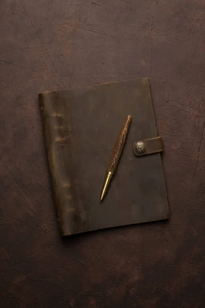 brown leather diary and pen on brown background or table