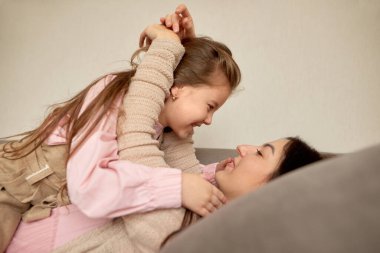 Gülümseyen anne, rahat evinde birlikte dinlenen genç kızı kucaklıyor. Kapatın sarılmaları ve mutlu yüzleri