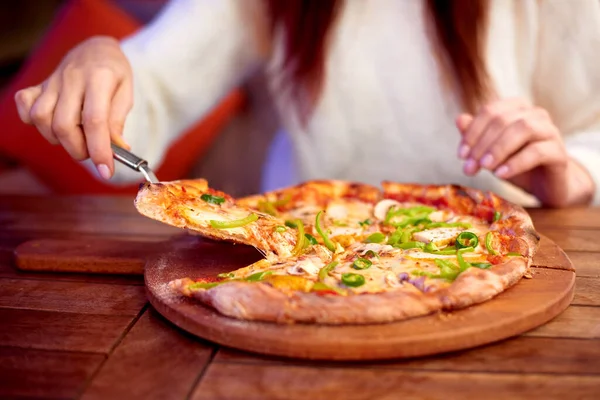 woman eat pizza at home. woman Hand takes a slice of sliced Pizza with Mozzarella cheese, tomatoes, pepper, olive. Italian pizza Margherita or Margarita on wooden table background