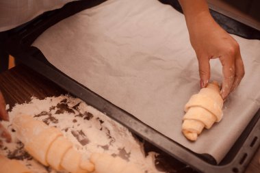 Kadın elleriyle kruvasan pişiriyor.