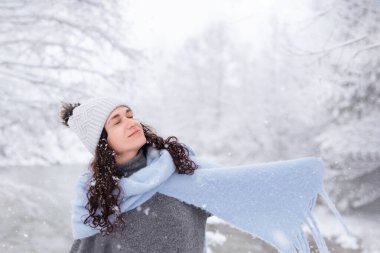 Karlı ormanda karın altında dönen bir kadın.