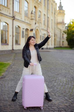 Valizli kadın şehir merkezinde el sallıyor.