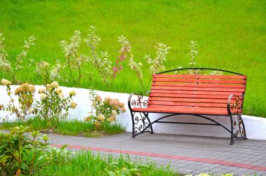 İlginç geometrik şekilli ahşaptan yapılma banklar parktaki yeşil çimlerin üzerine kurulur.