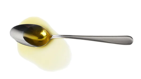 Steel spoon in a puddle of olive oil — Stock Photo, Image