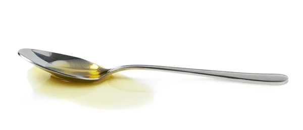 Steel spoon in a puddle of olive oil — Stock Photo, Image