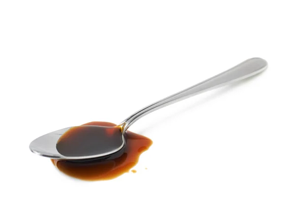 Steel spoon in a puddle of worchester sauce — Stock Photo, Image