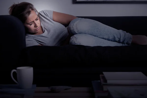 Vrouw in pijn op een bank — Stockfoto