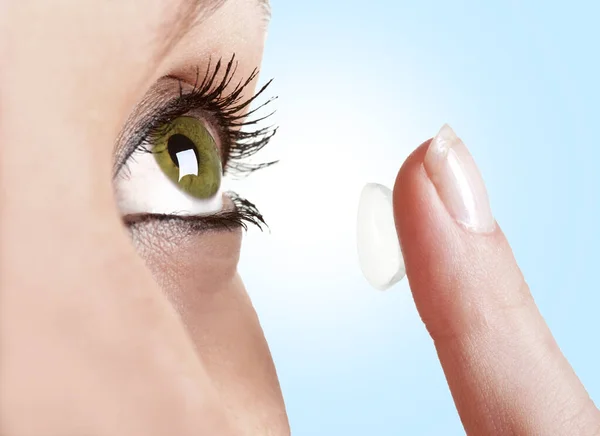 Closeup Woman Inserting Contact Lens Her Eye Blue Background Stock Photo