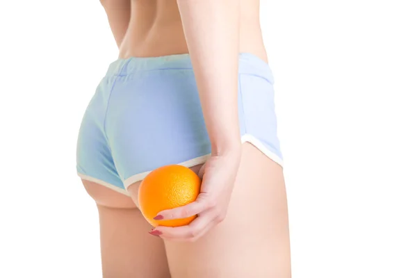 Kobieta trzyma pomarańczowy przeciwko jej uda — Zdjęcie stockowe