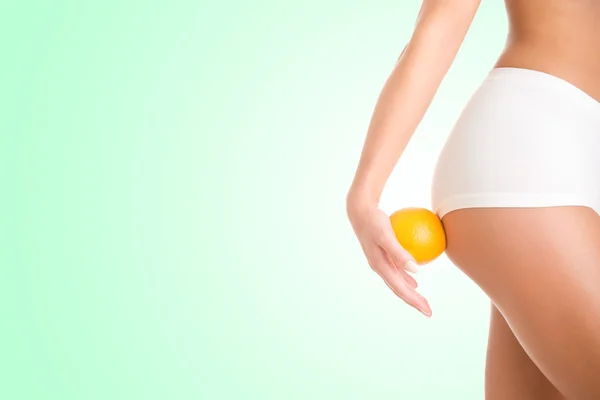 Woman Holding an Orange Against Her Thighs — Stock Photo, Image