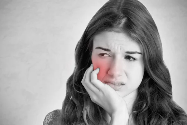 Primo piano di una donna con un mal di denti. Bianco e nero con un'area rossa intorno al dolore . — Foto Stock
