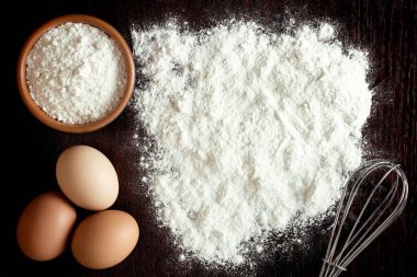 Buğdaylı un, yumurta, merdane, ahşap zemin üzerinde kaşık. Fırın ürünleri için malzemeler