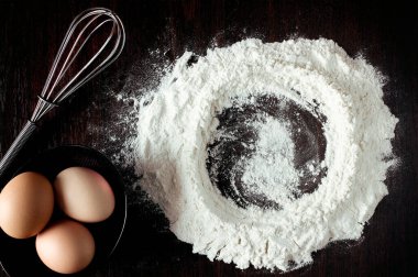 Buğdaylı un, yumurta, merdane, ahşap zemin üzerinde kaşık. Fırın ürünleri için malzemeler