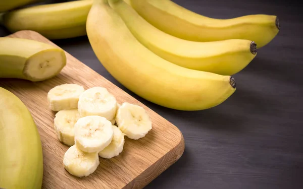 A bunch of bananas and a sliced banana   on a table, delicious, natural.