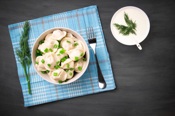 Мясные пельмени - российские пельмени, пельмени с мясом на тарелке на черном фоне